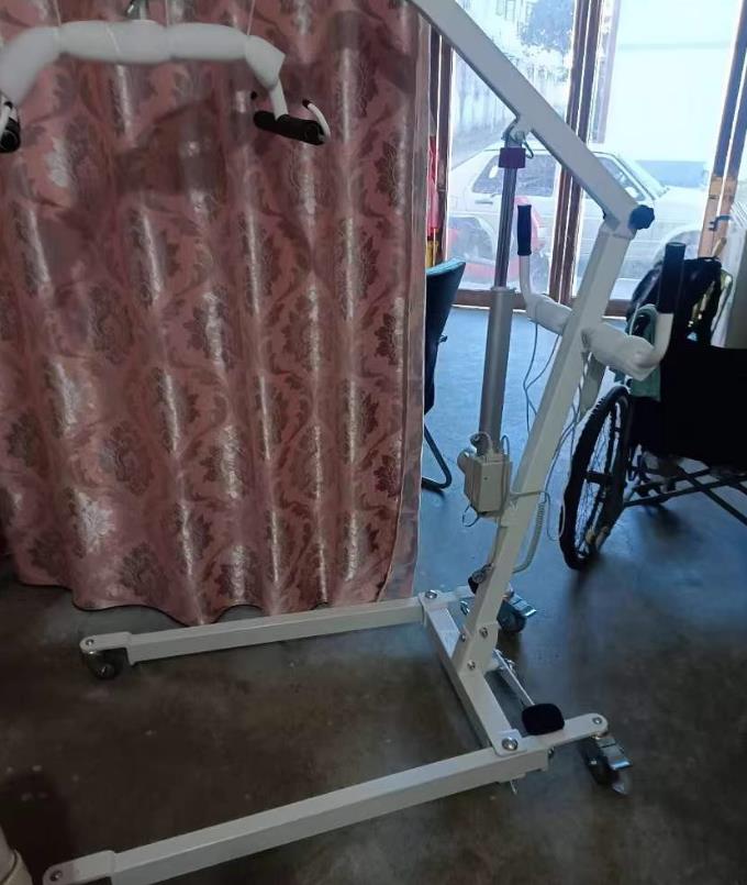 Cuidador que utiliza sistemas de elevación de pacientes para trasladar al paciente de forma segura de la cama a la silla de ruedas